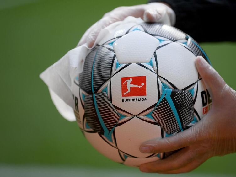 Hände in Einweghandschuhen wischen einen Bundesliga-Spielball mit einem Tuch ab